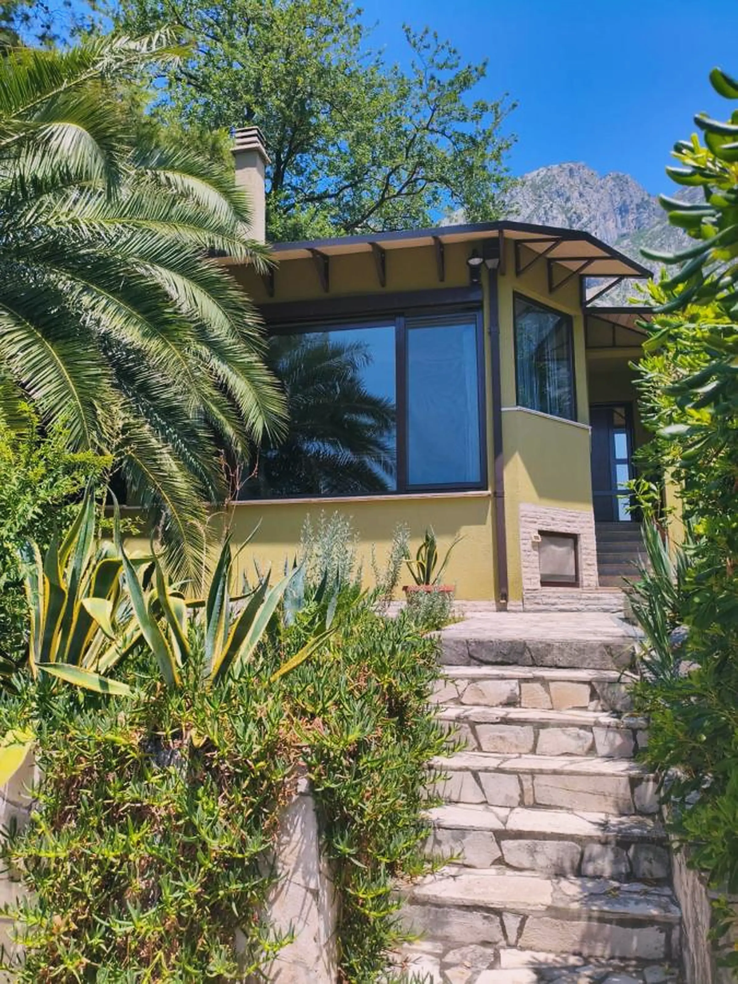 Photo of the house, green garden, and view over the Bay of Kotor